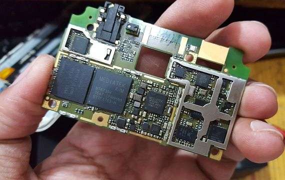 Photo of a person's hand holding a smartphone's motherboard.