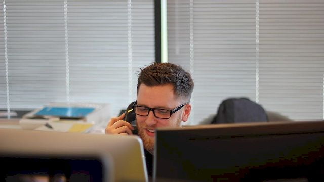 Image of a man using a telephone in an office.