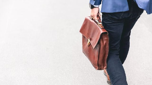Image of a man walking while holding a briefcase.