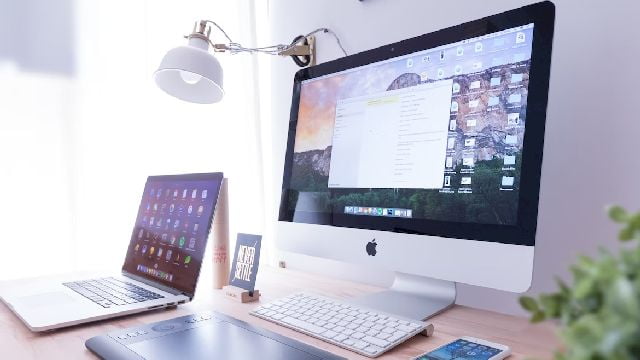 Image of a mac desktop, a laptop, a tablet and a smartphone on a table.