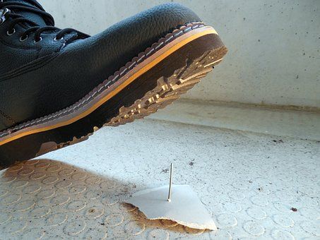 Photo of a person's boot about to step on a nail.