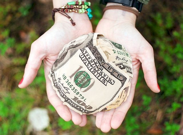 Image of a woman's open hands holding dollar bills.