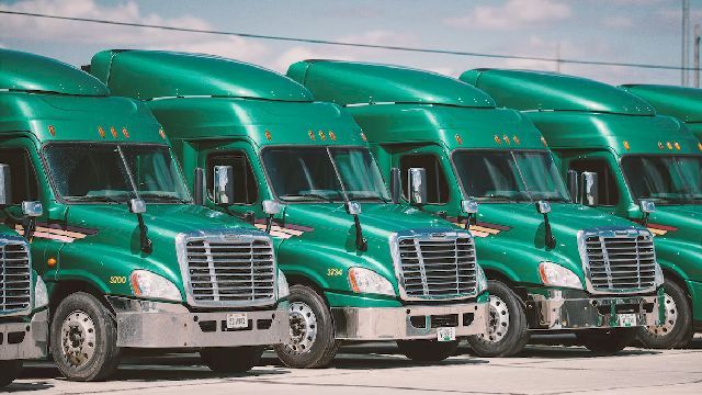 Photo of green trucks parked.