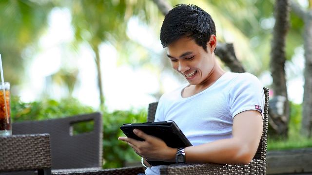 Photo of a man using a tablet outdoors.