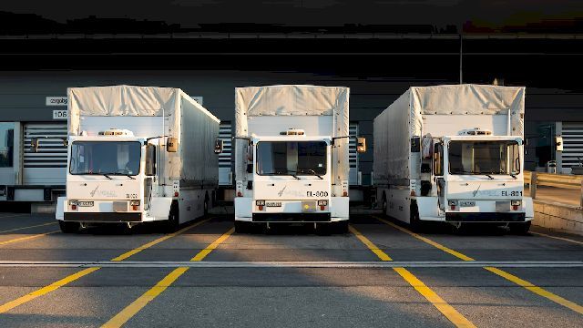 Photo of three white trailer trucks parked.