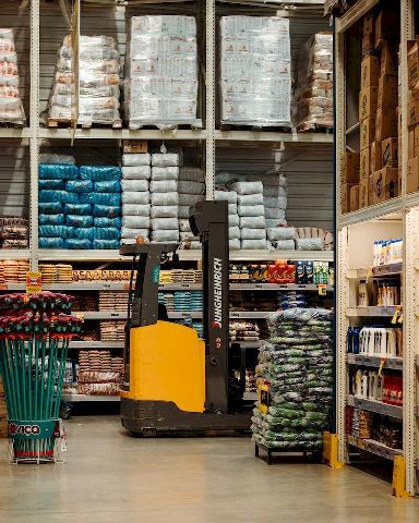 Photo of a forklift in a warehouse with pallet racks.