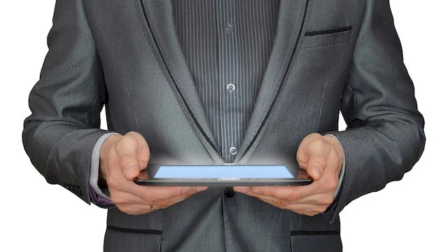 Image of a man in a suit holding a tablet.